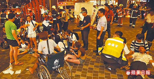 待送医  多名伤者在车站外或坐或躺，接受检伤后等候送医。